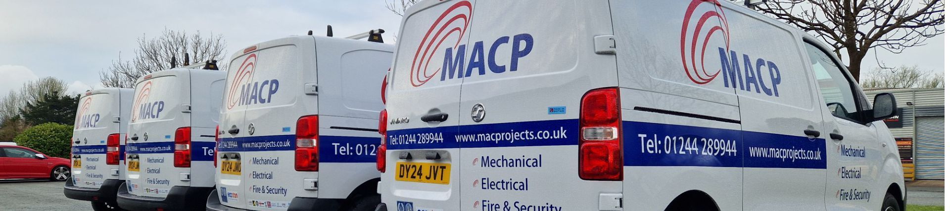 A row of white MACP vans parked outdoors. They have the company logo on the back doors and blue and red stripes.