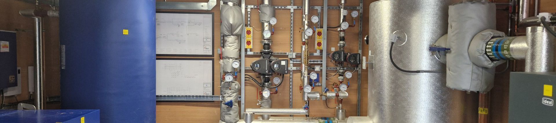 Piping and equipment in an industrial setting, including a blue tank, pumps, and valves.