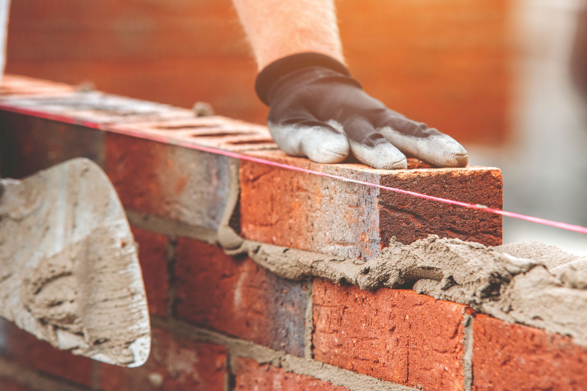 Woman in straw hat smiles, holding wine glass near a lake.