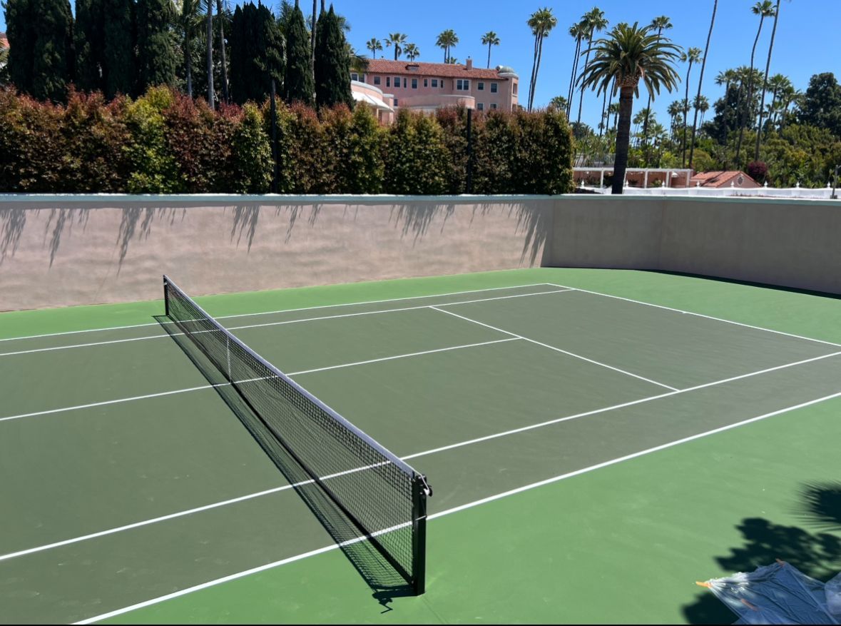 A tennis court with palm trees in the background