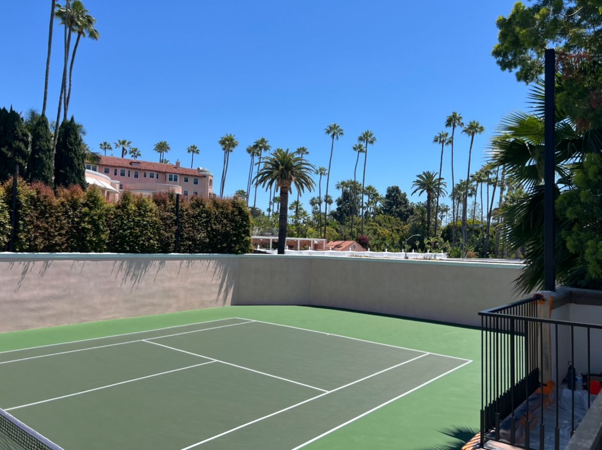 A tennis court with palm trees in the background