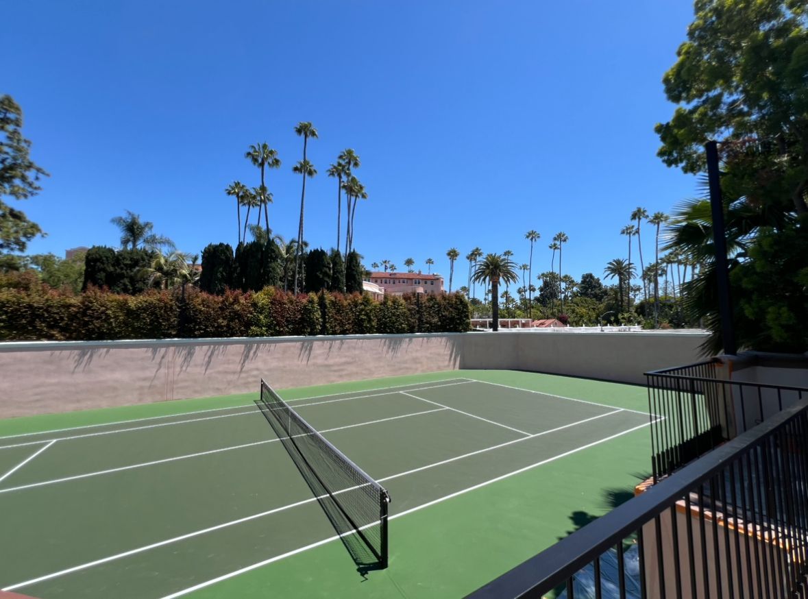 A tennis court with palm trees in the background