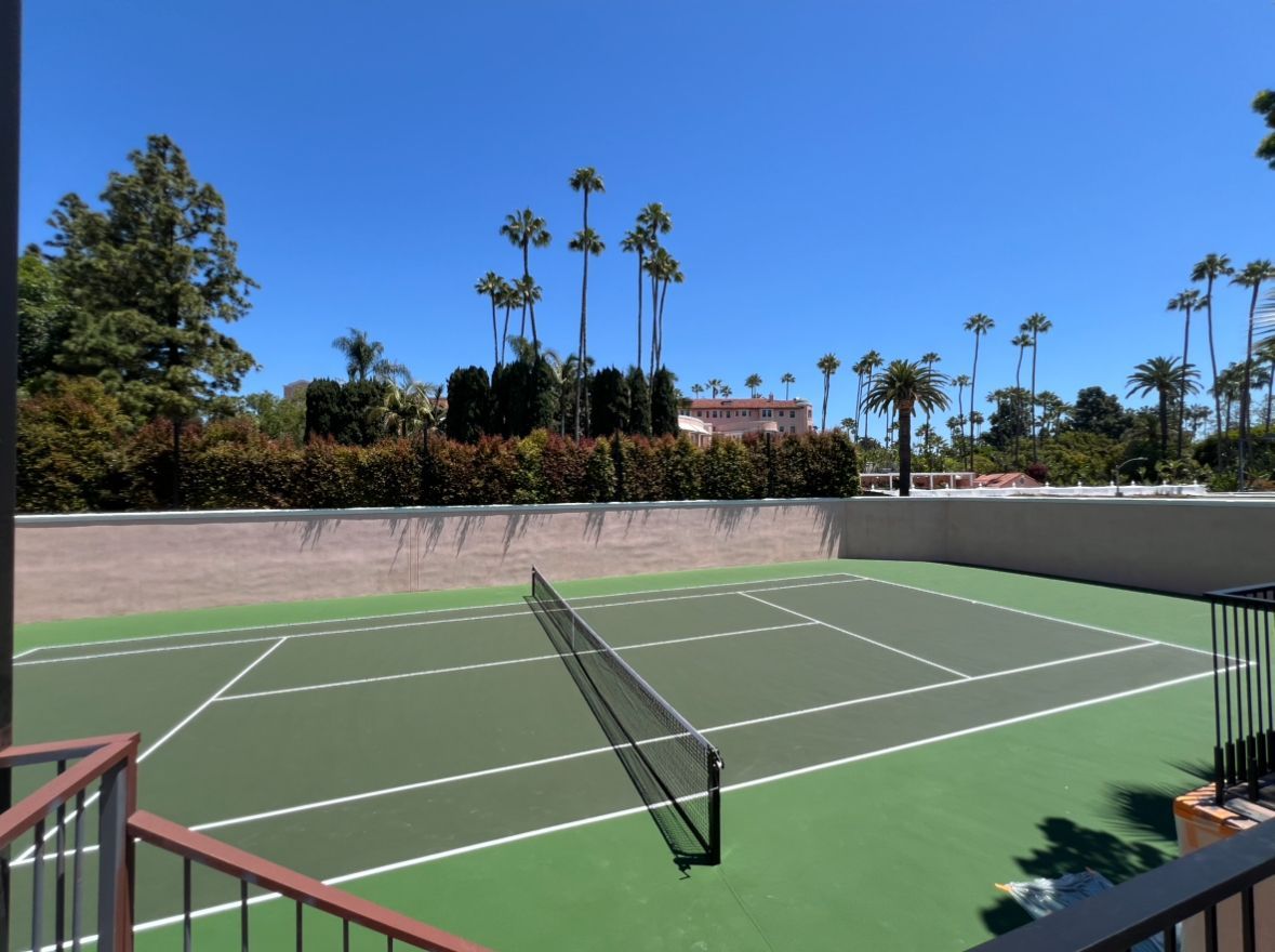 A tennis court with palm trees in the background