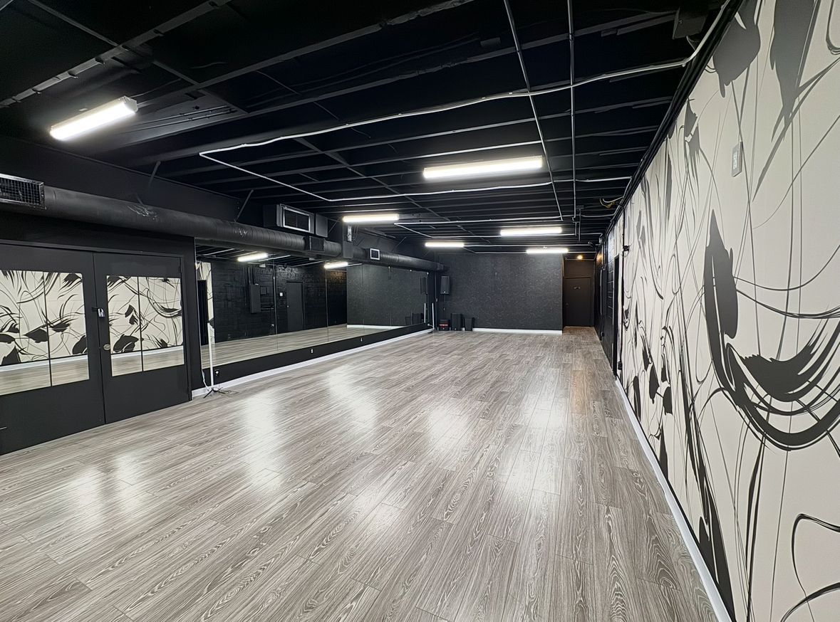 An empty dance studio with a large mirror on the wall.