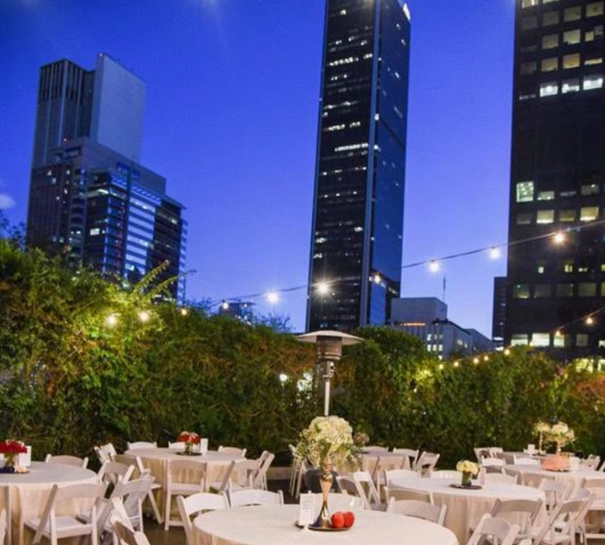 Tables and chairs are set up in front of tall buildings