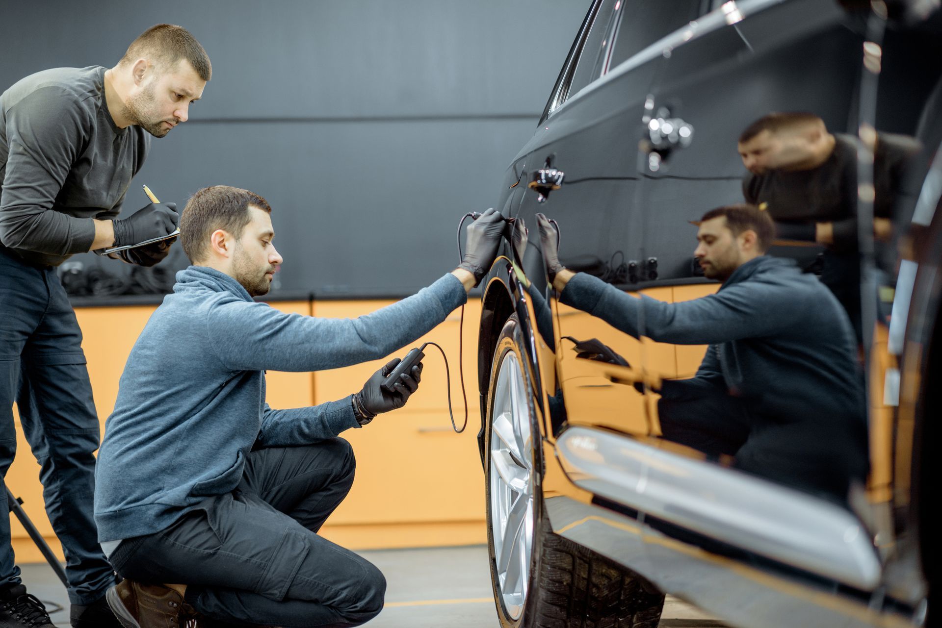 Two men are working on a car in a garage.