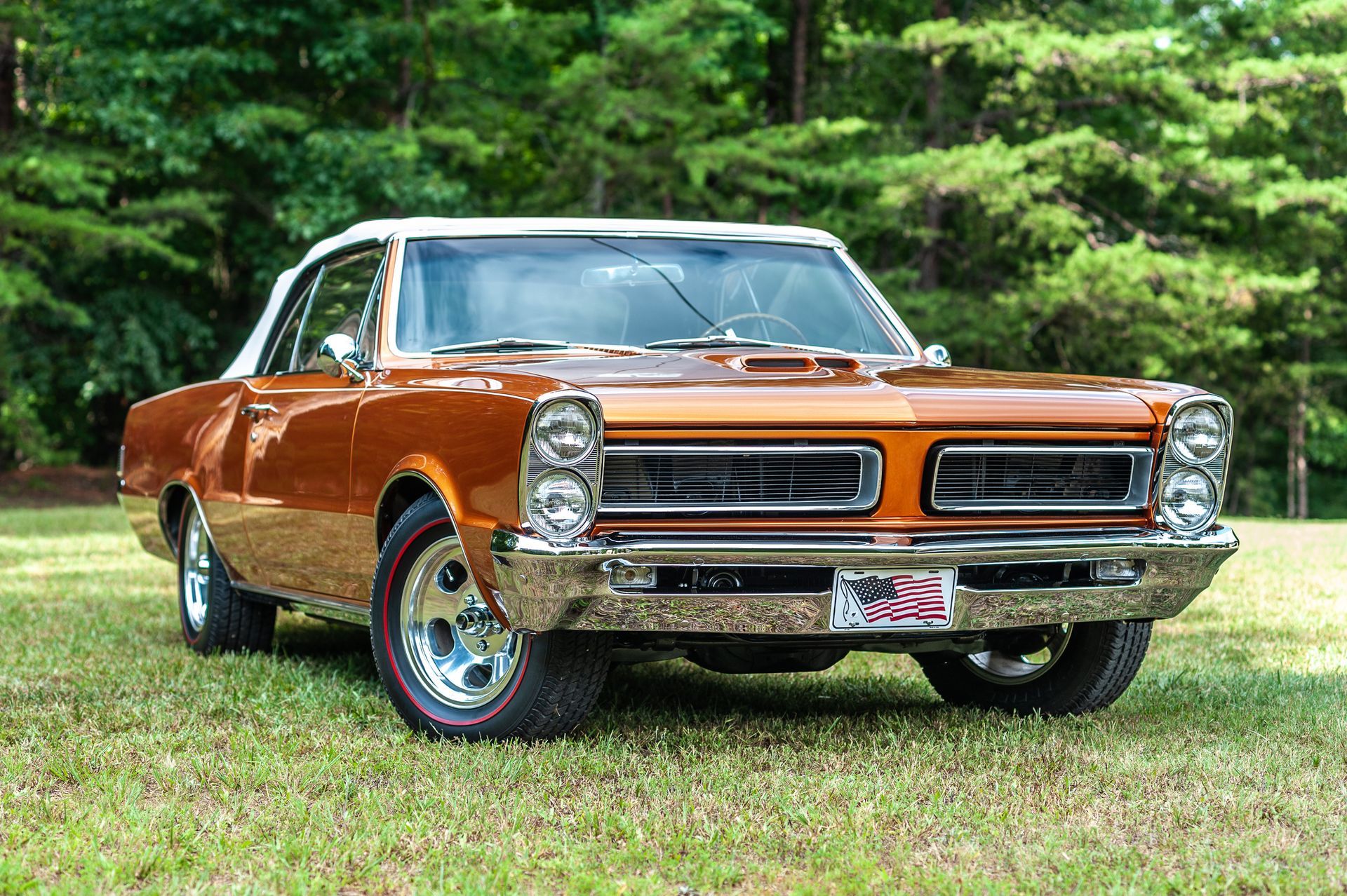 A brown and white car is parked in a grassy field.