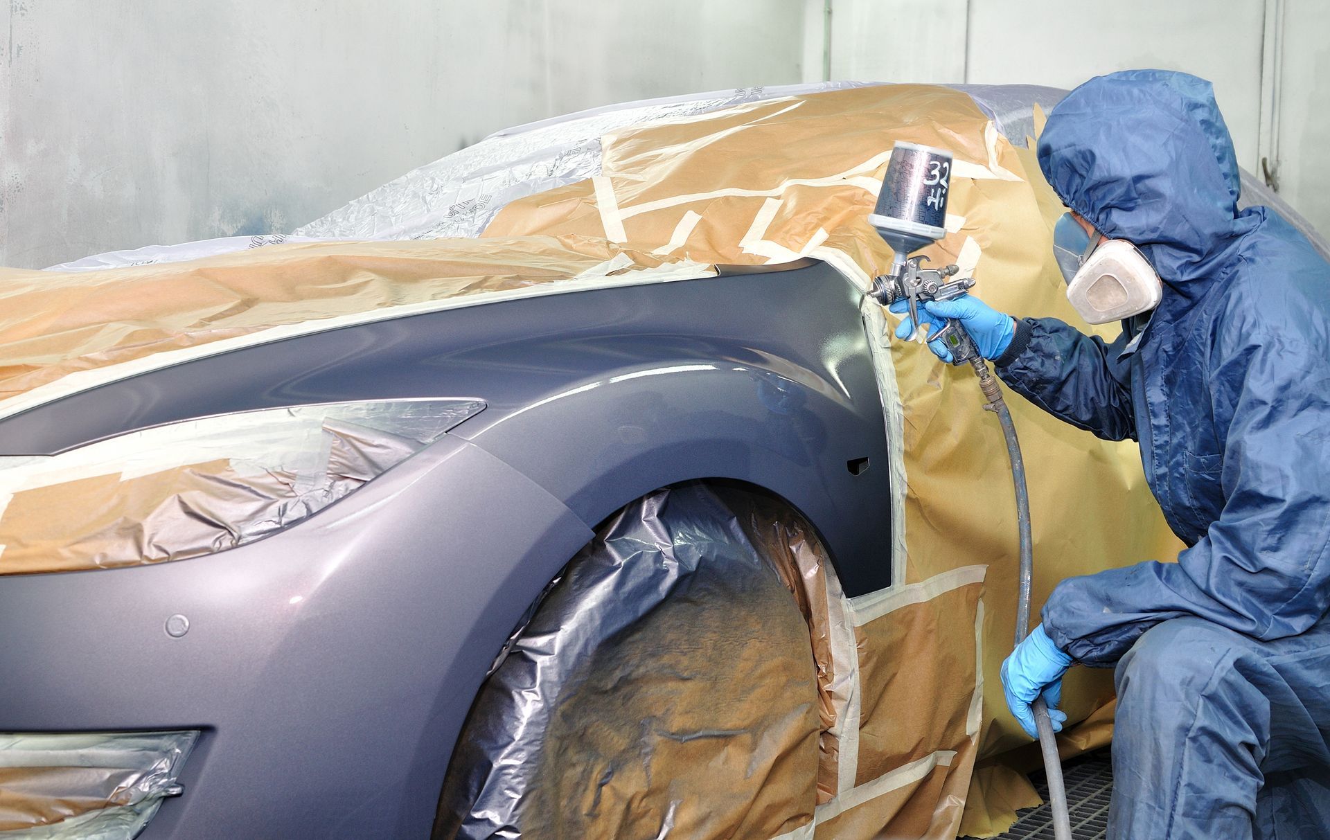 A man is spray painting a car in a garage.