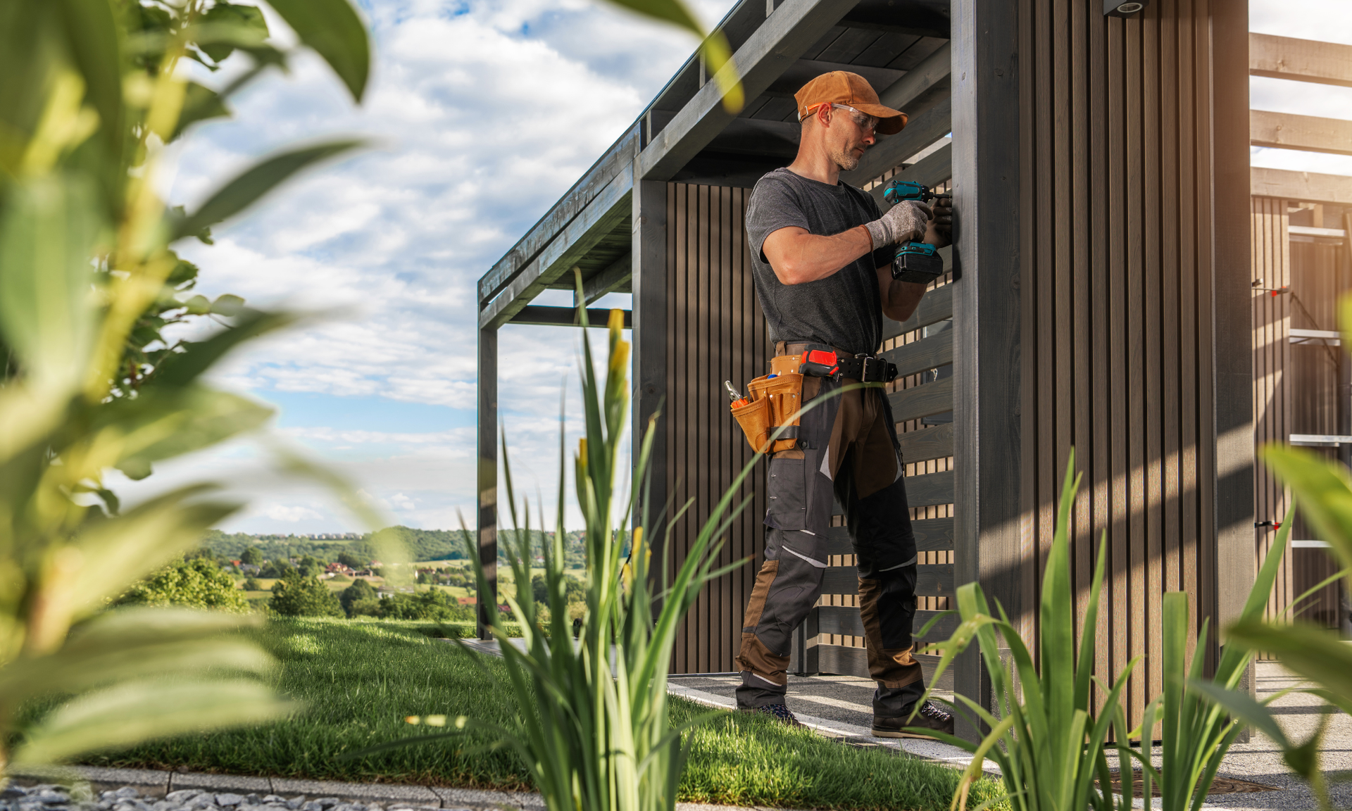 Een timmerman gebruikt een boormachine om een ​​houten constructie buiten te bewerken.