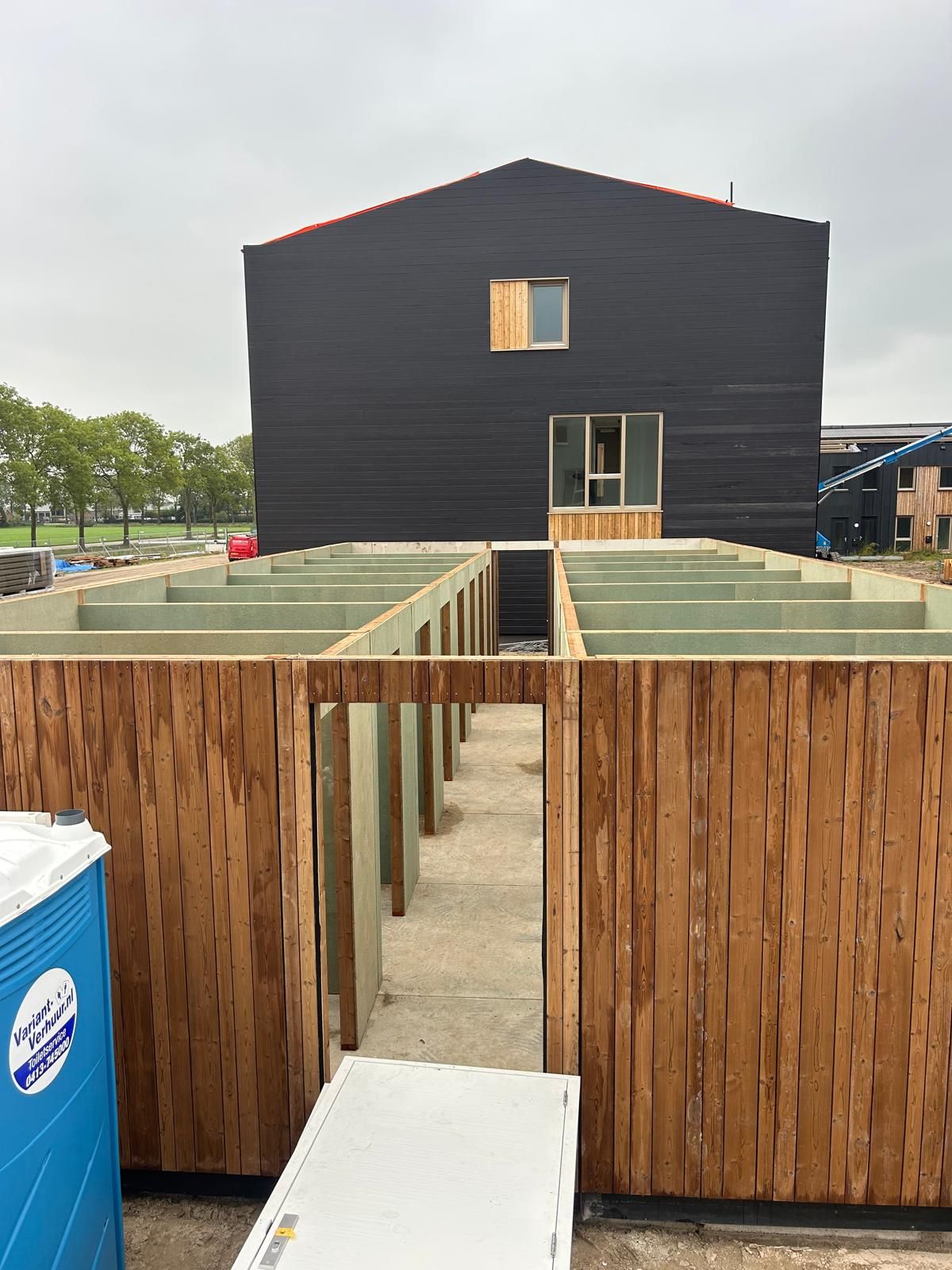 Een timmerman gebruikt een boormachine om een ​​houten constructie buiten te bewerken.