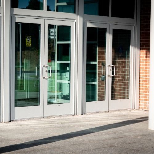 Glass double doors at building entrance with metal handles and brick wall