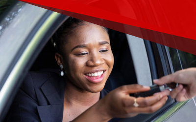 Woman smiling as she receives a car key at a vehicle window with a red awning overhead