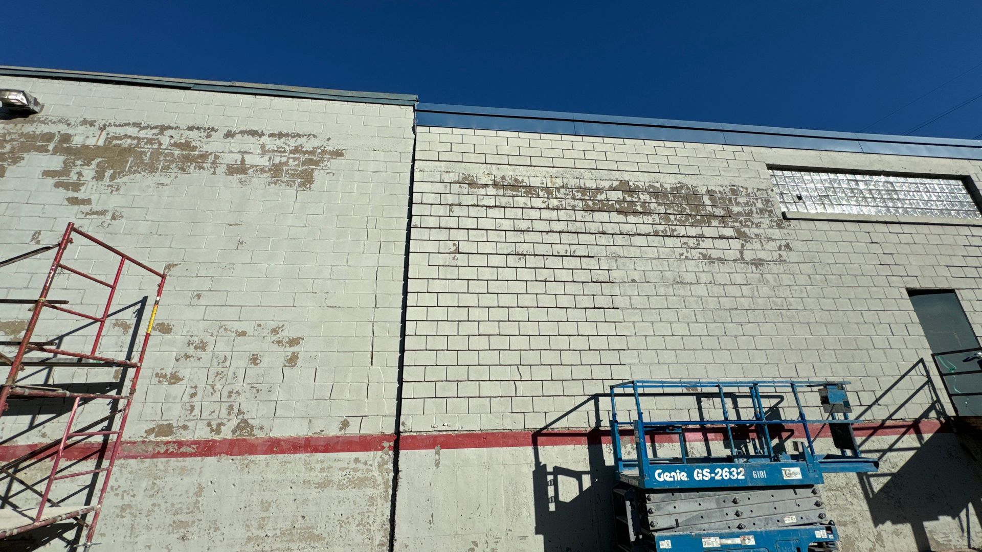 Building exterior with peeling paint and a raised work platform.