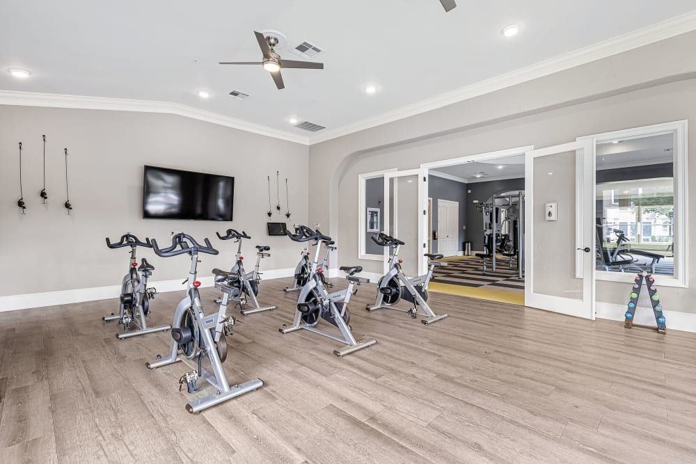 A gym with a lot of exercise bikes and a flat screen tv at Marquis at The Cascades in Tyler, TX.