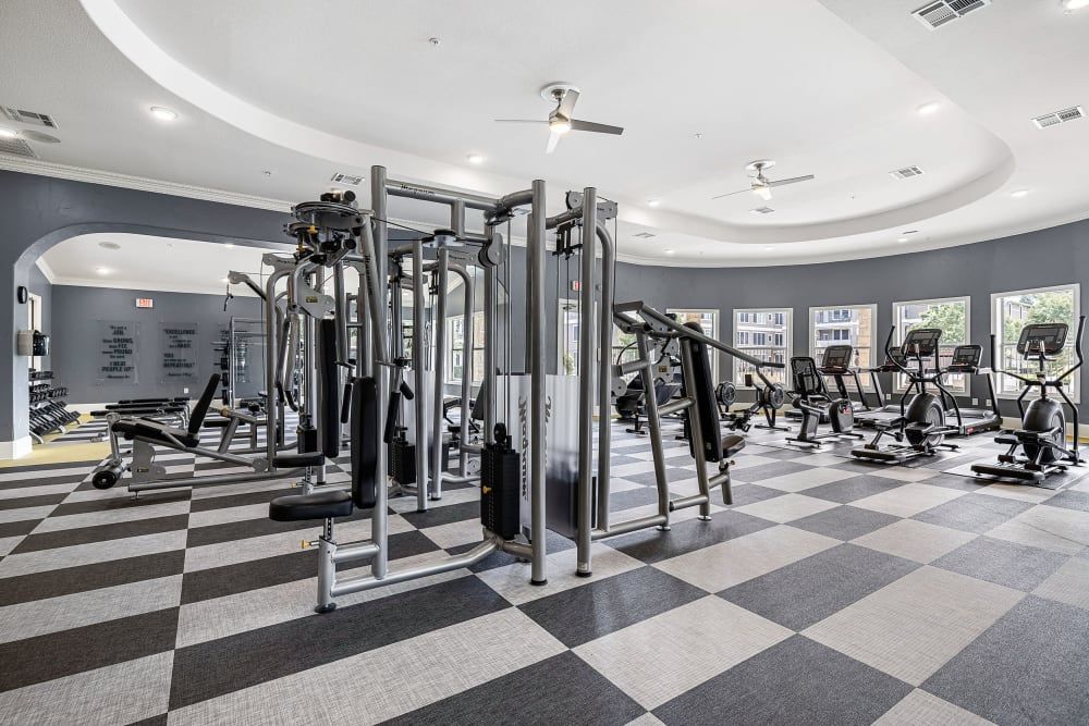 Apartment fitness center filled with lots of exercise equipment and a checkered floor at Marquis at The Cascades in Tyler, TX.