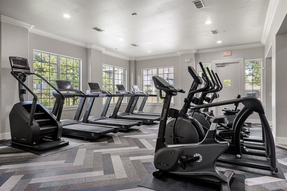 A gym with a lot of treadmills and exercise bikes at Marquis at The Cascades in Tyler, TX.