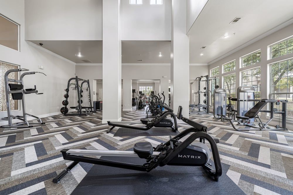 A large gym with a lot of equipment and a rowing machine at Marquis at The Cascades in Tyler, TX.