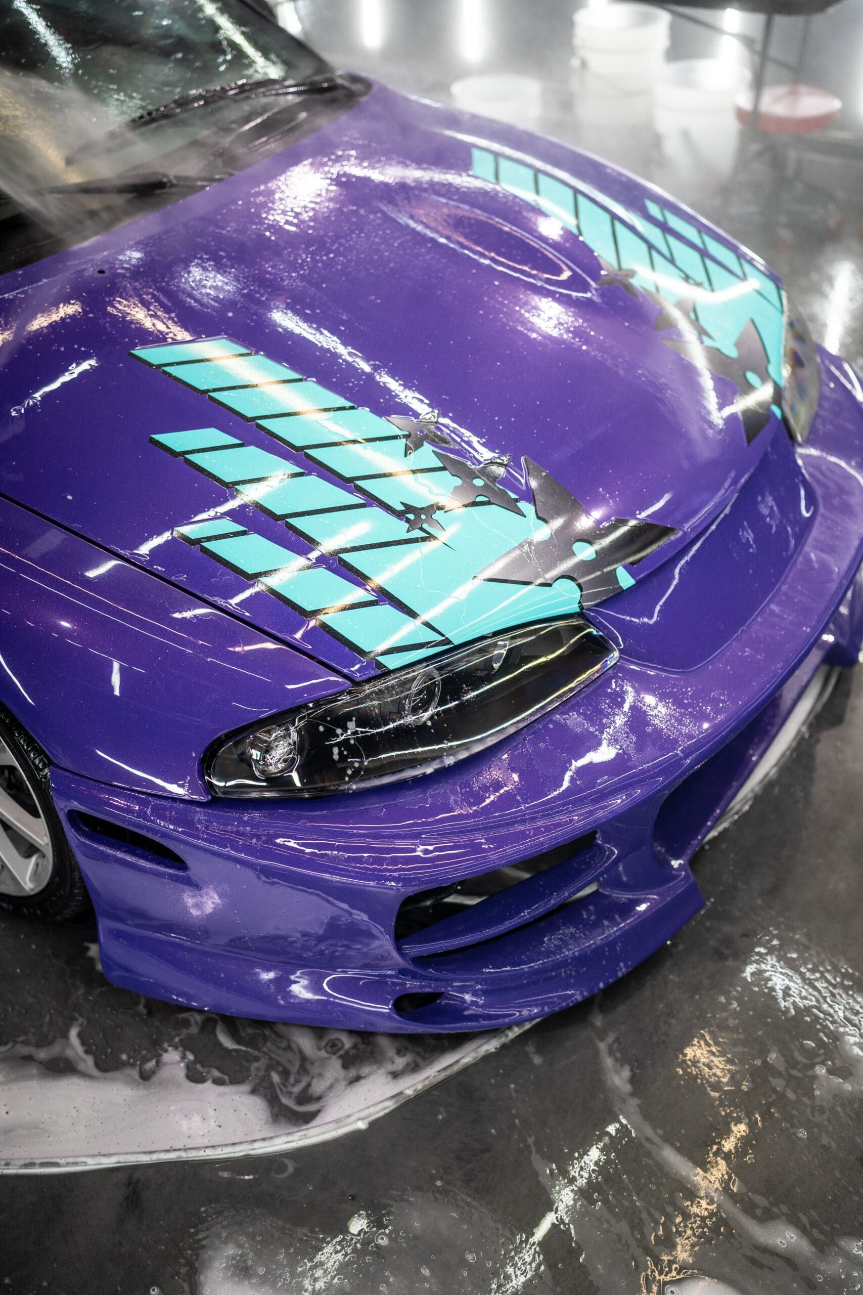 A purple car with a blue stripe on the hood