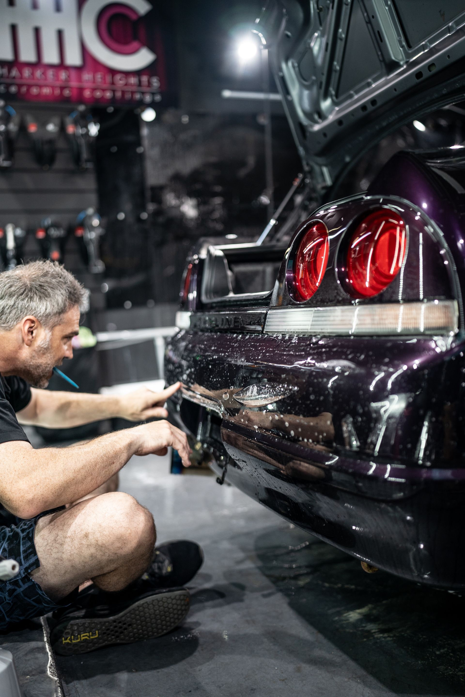 A man is working on the back of a purple car.