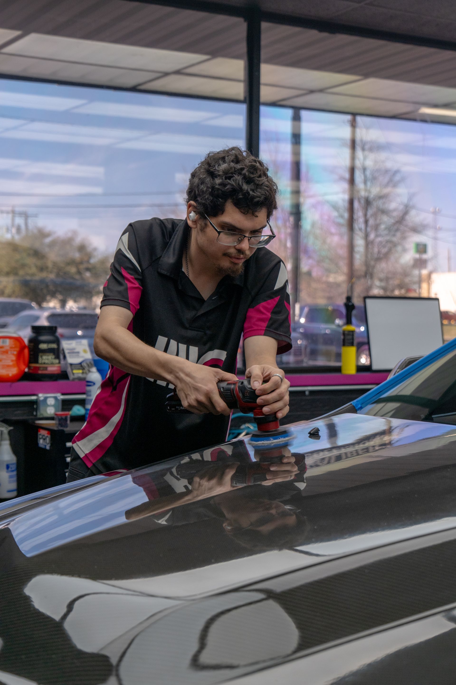 Professional detailer polishing the carbon fiber hood of a Cadillac CTS-V during paint correction near Temple, TX.