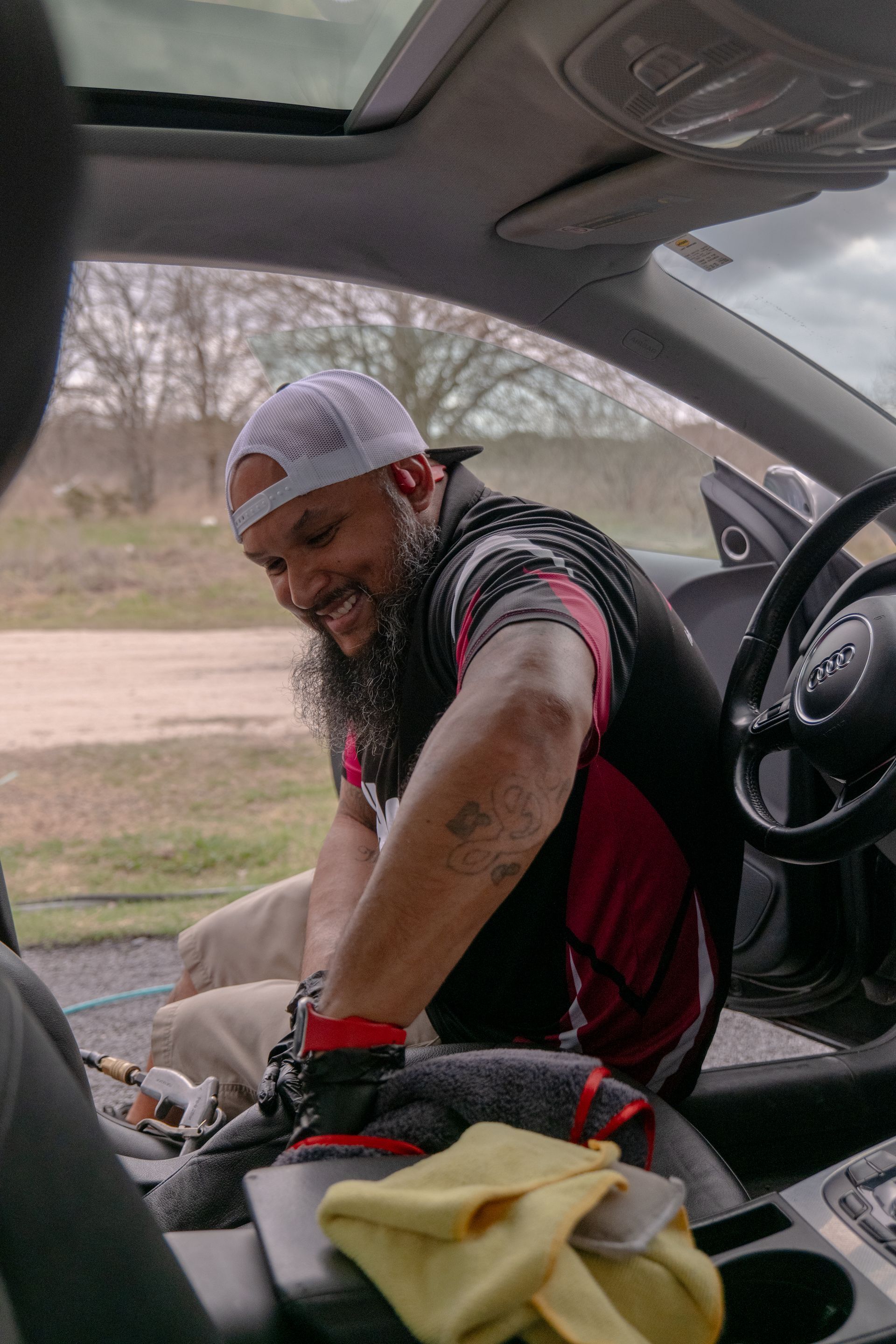 Person in black gloves wiping car door frame with red cloth. Interior with brown and black accents.