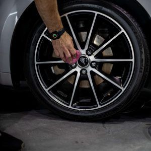 A person is cleaning a car wheel with a cloth.