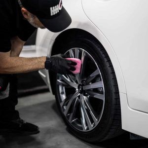 A man is cleaning a car wheel with a sponge.