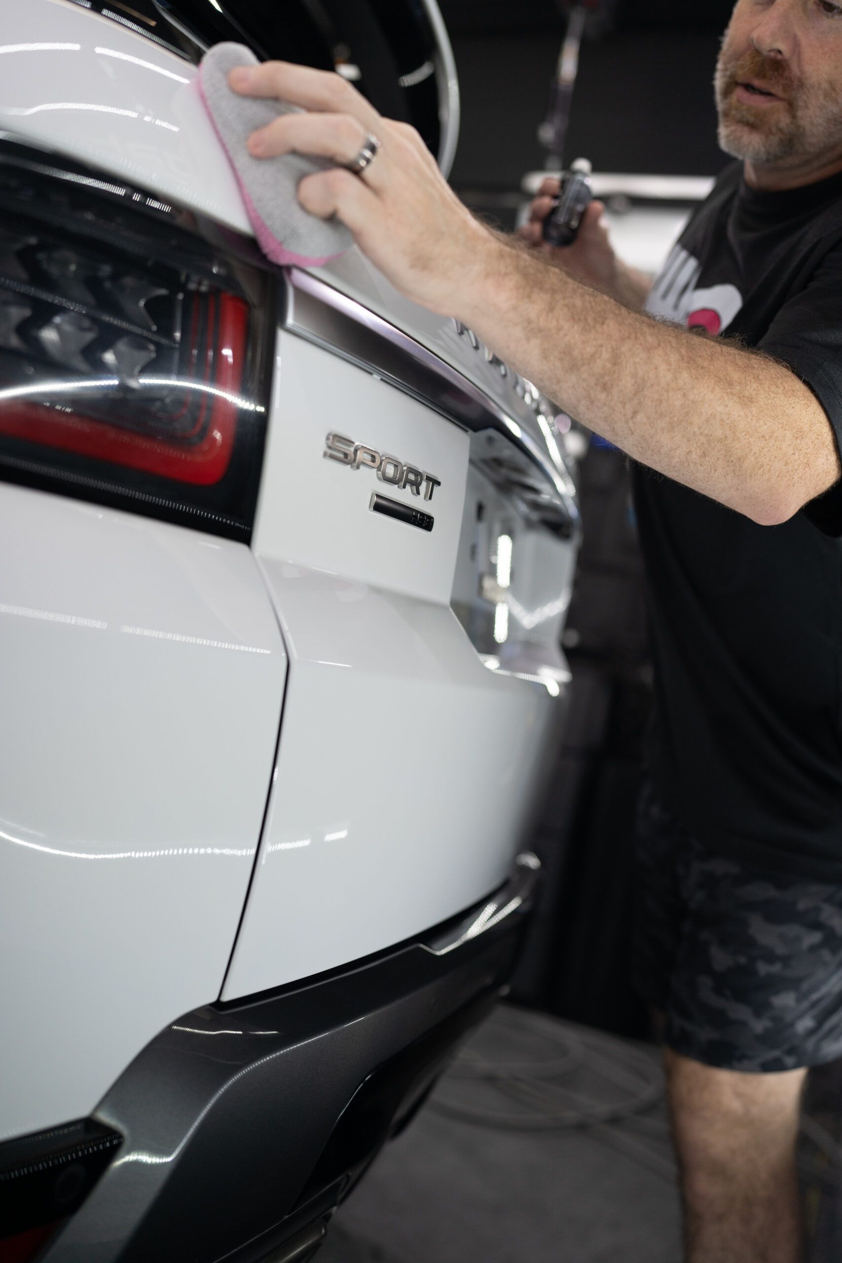 A man is polishing a white car with a sponge