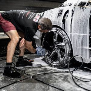 A man is washing a car with soap and water.