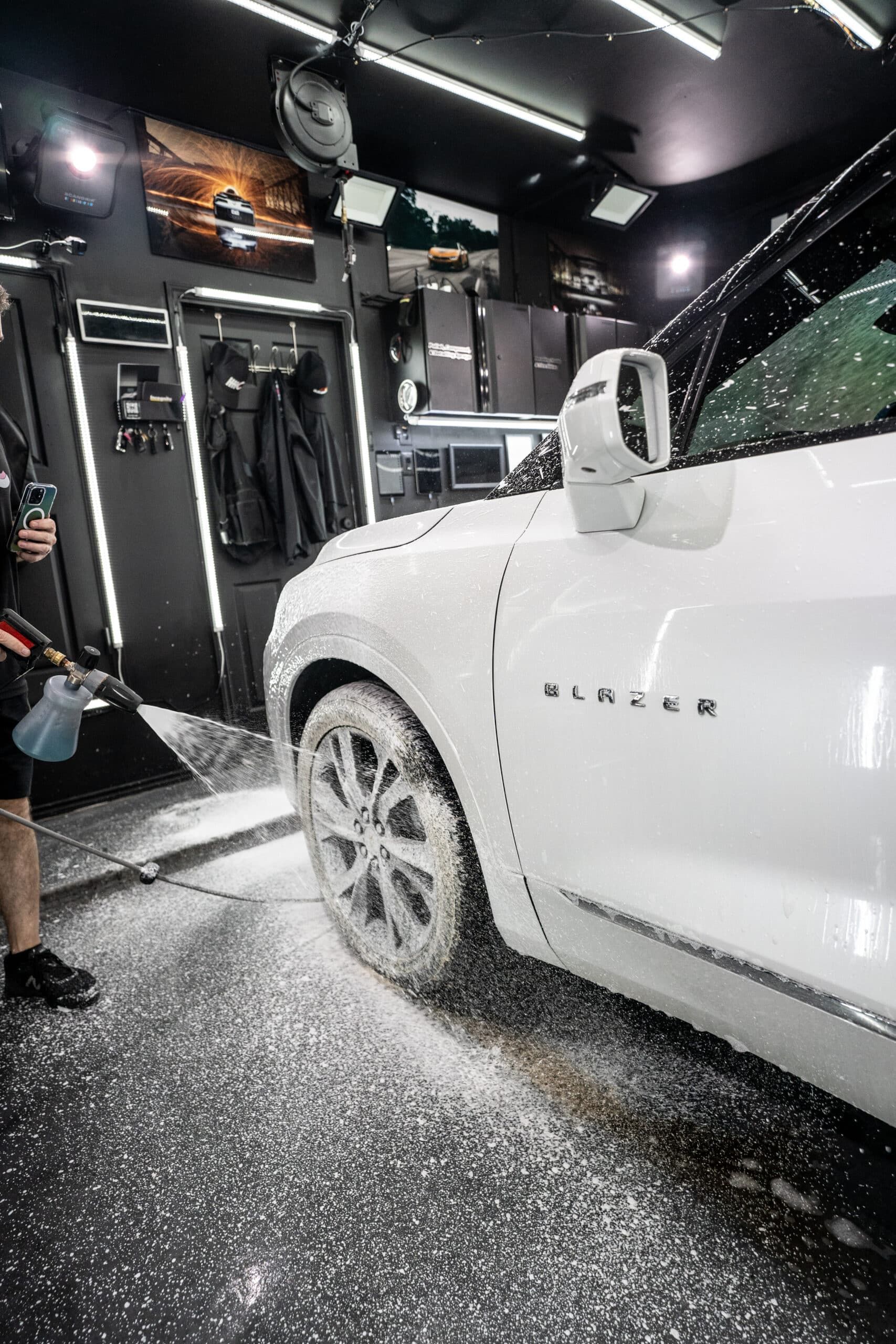 A man is washing a white suv in a garage.
