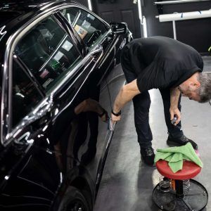 A man is working on a black car in a garage.