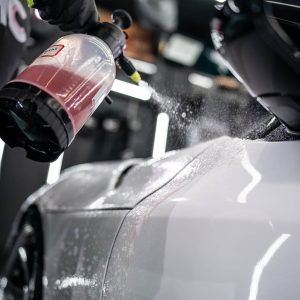 A person is spraying a car with a spray bottle.