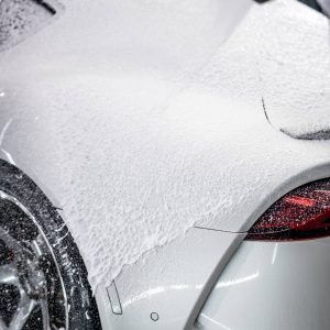 A close up of a white car covered in foam.