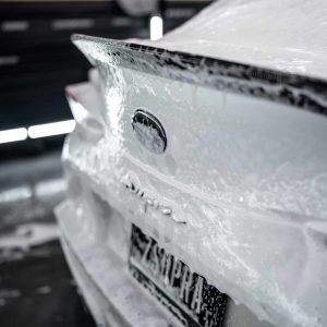 The back of a white car is covered in foam.