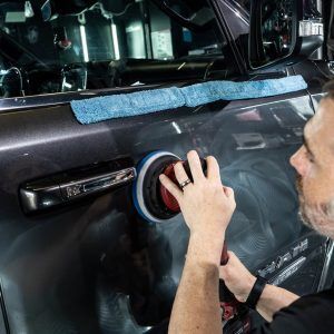 A man is polishing a car with a polisher.