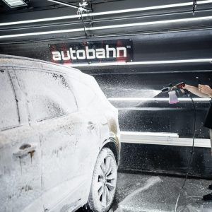 A person is washing a car with foam in a car wash.
