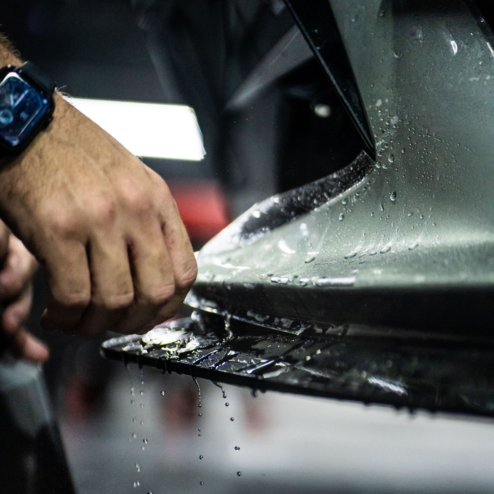 A man wearing a watch is cleaning a car