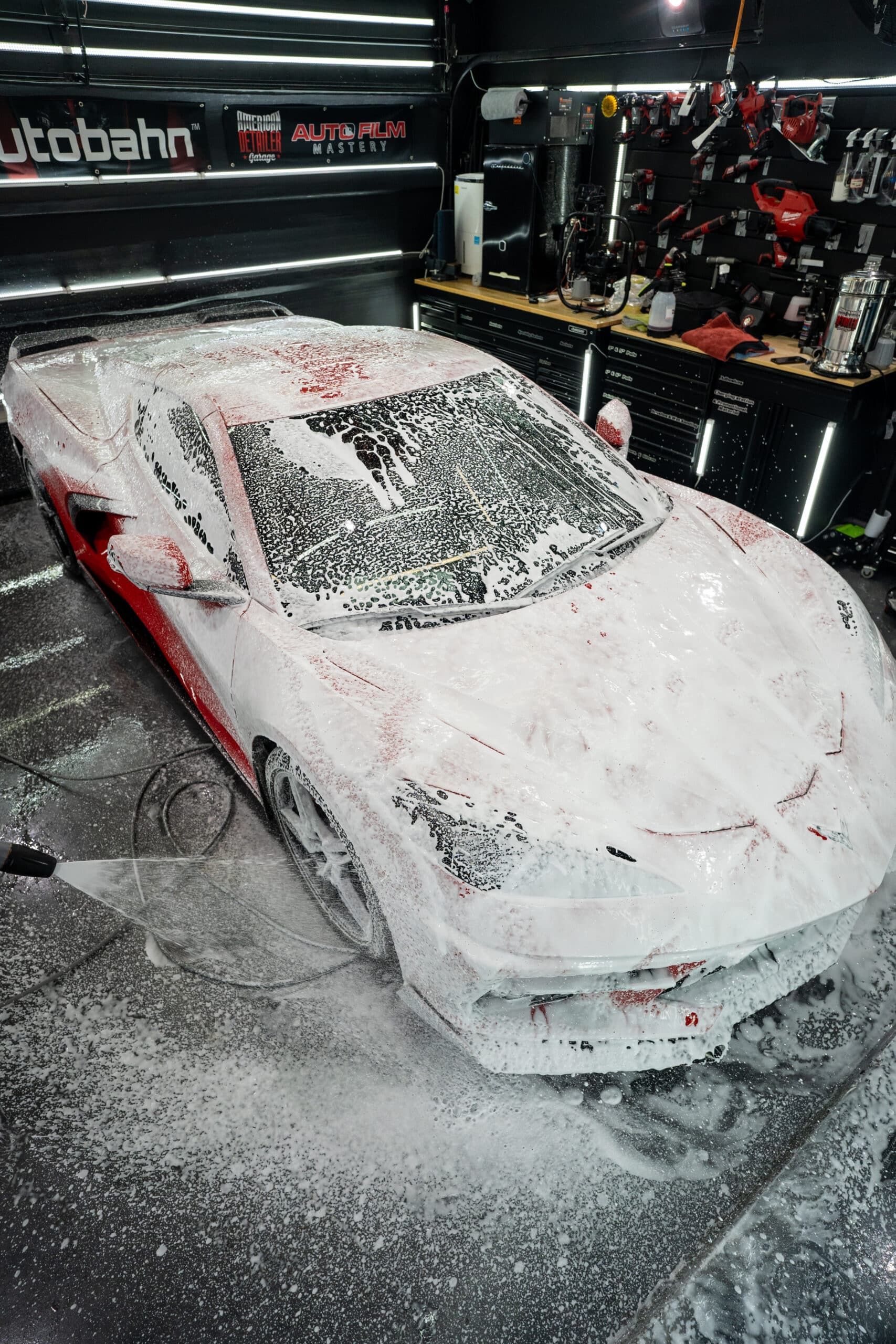 A car is covered in foam in a garage.