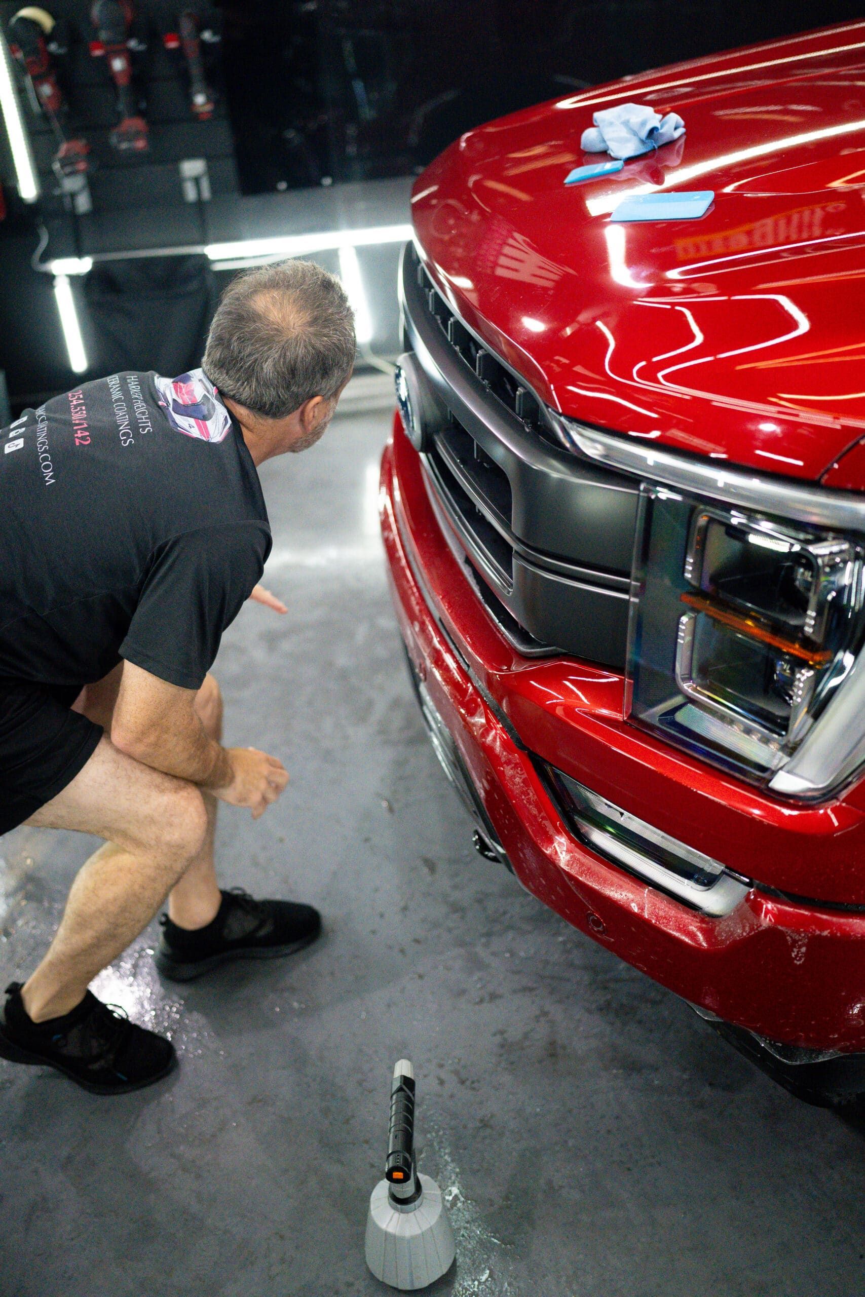 A man is kneeling down in front of a red truck.
