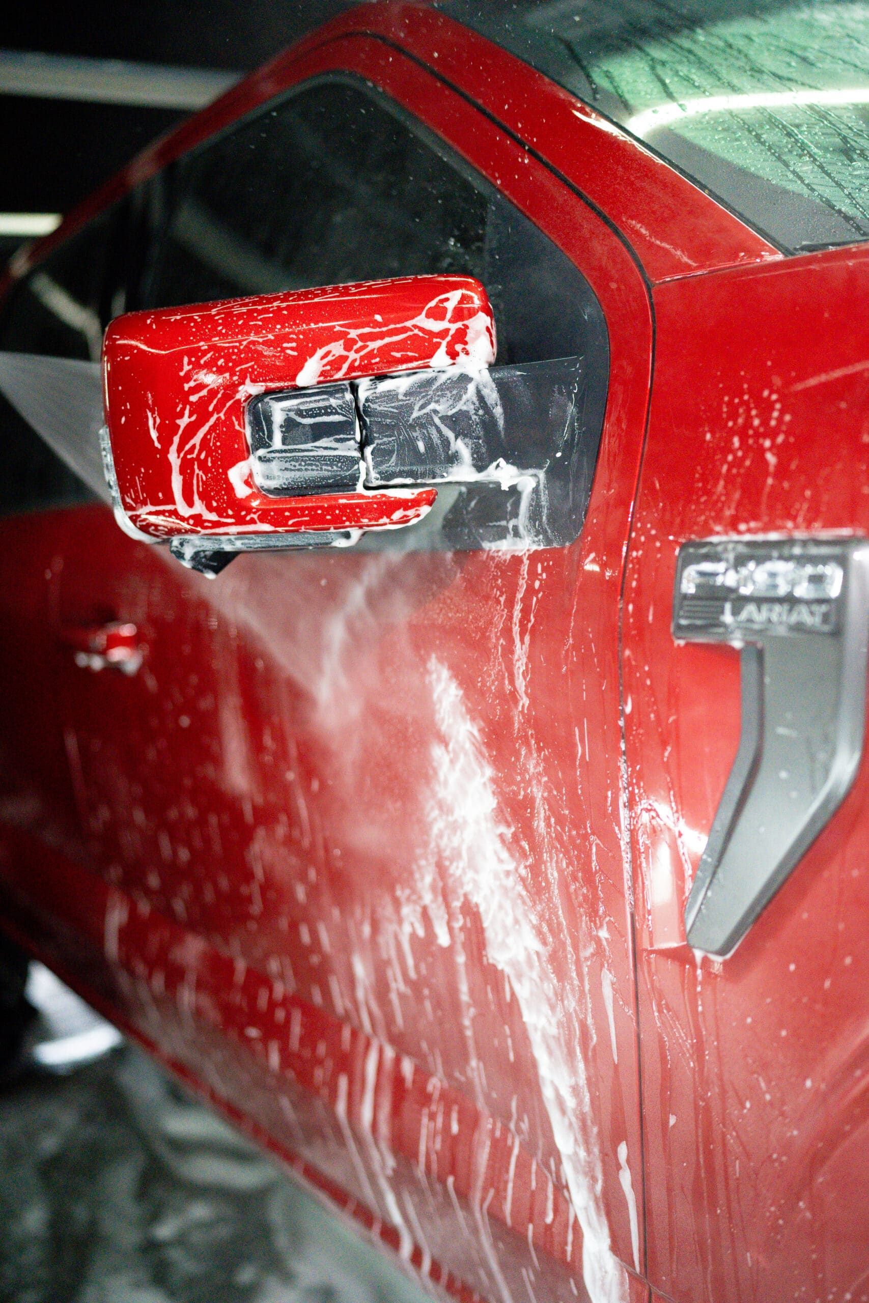 A red ford truck is being washed with soap and water