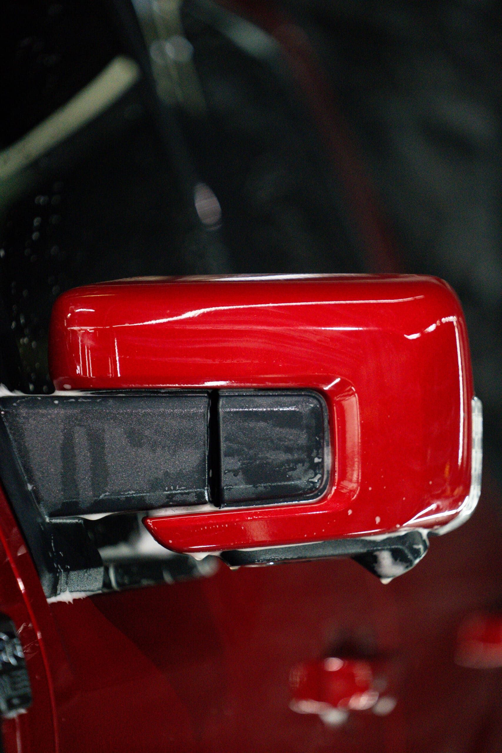 A close up of a red car side mirror