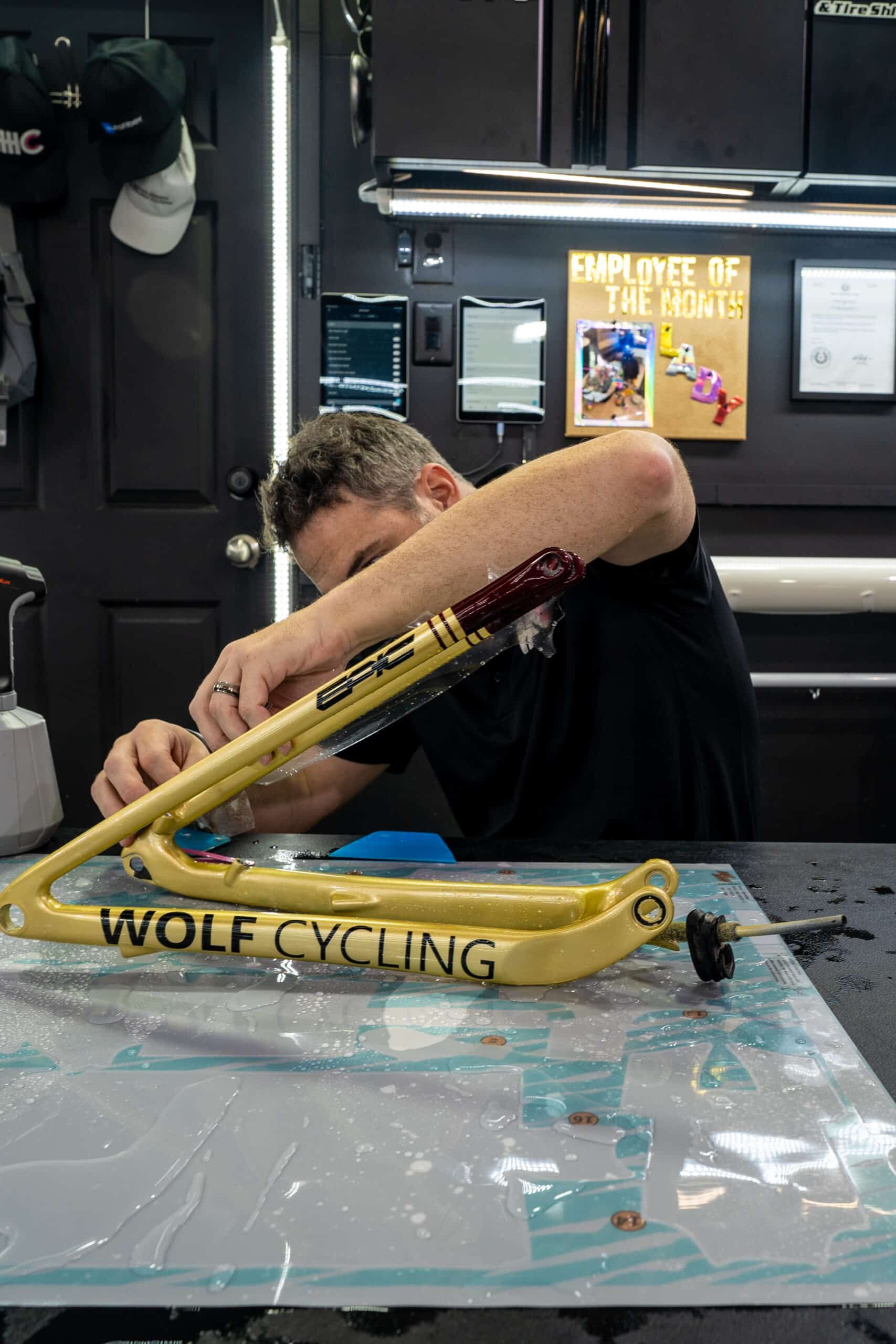 A man is working on a bicycle frame in a garage.