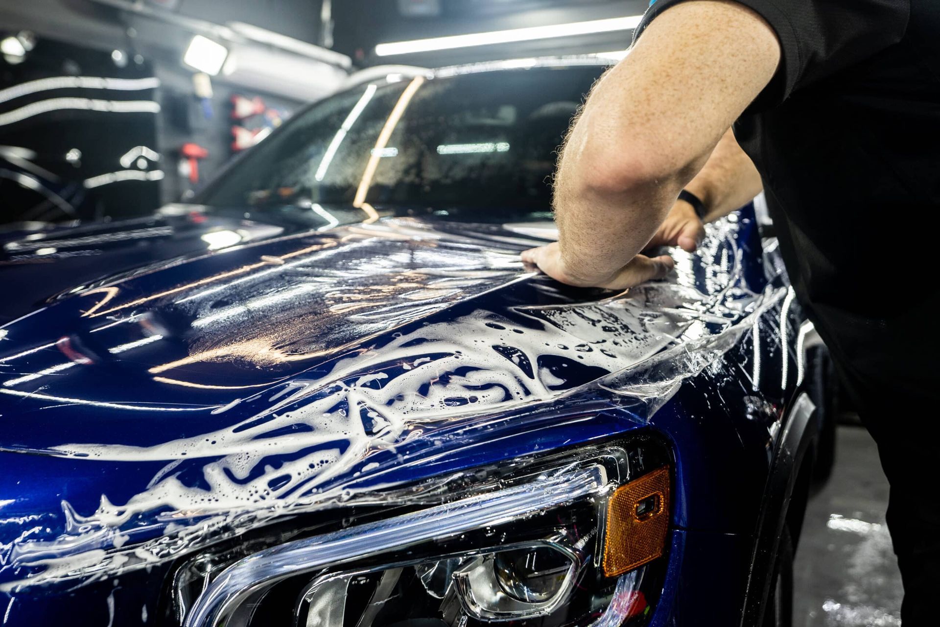 A man is washing a blue car in a car wash.