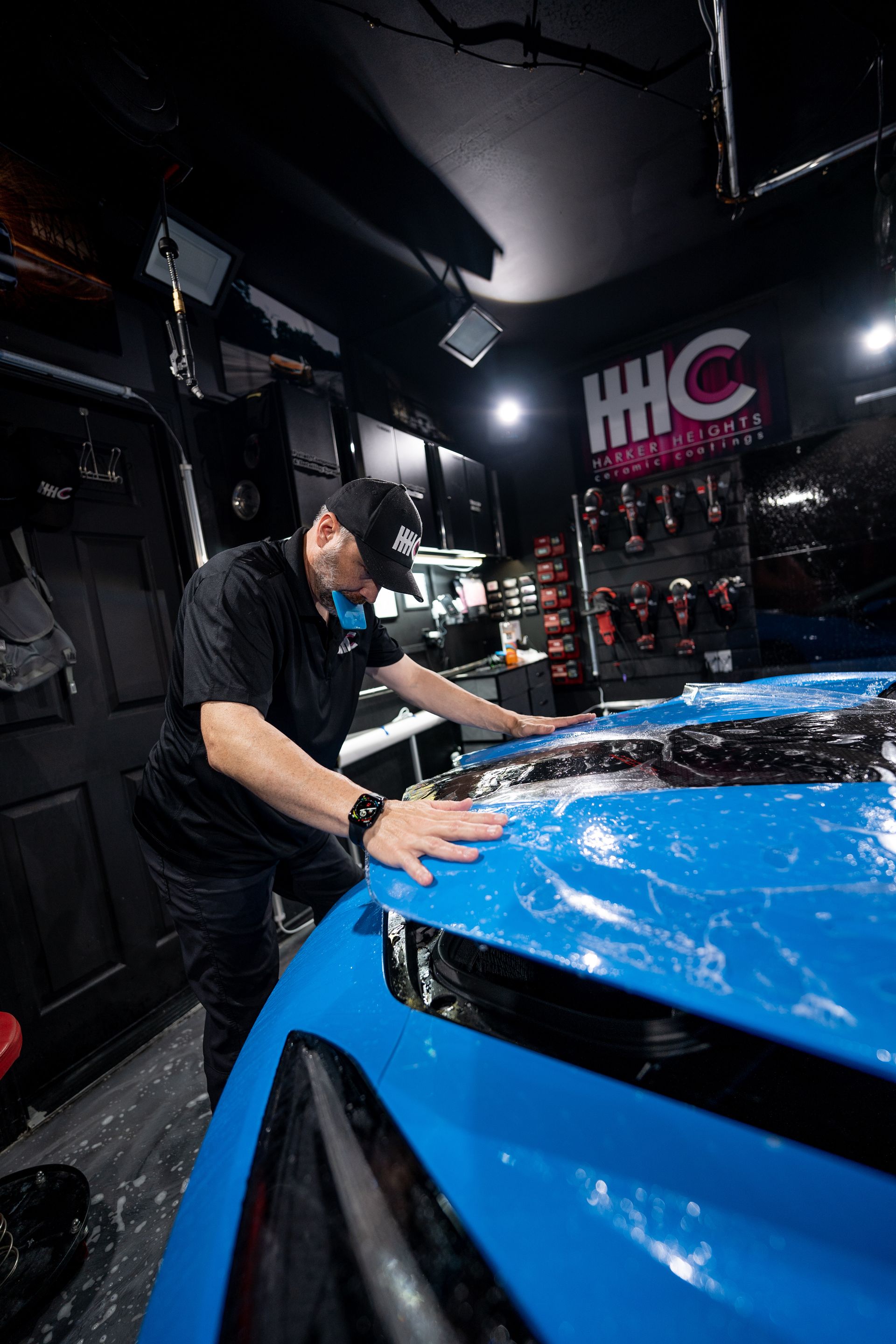 A man is working on a blue car in a garage.