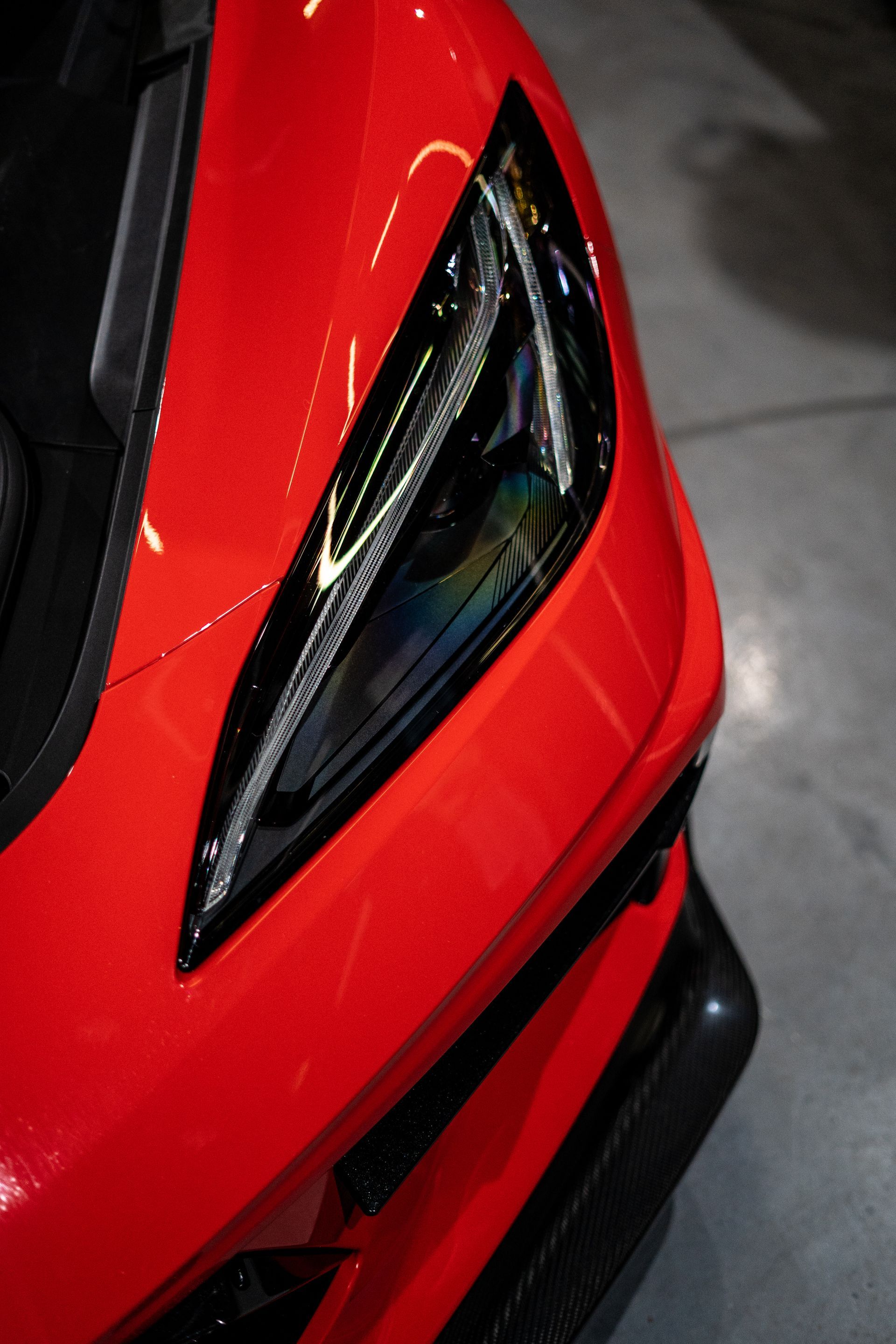 A close up of the headlight of a red sports car.