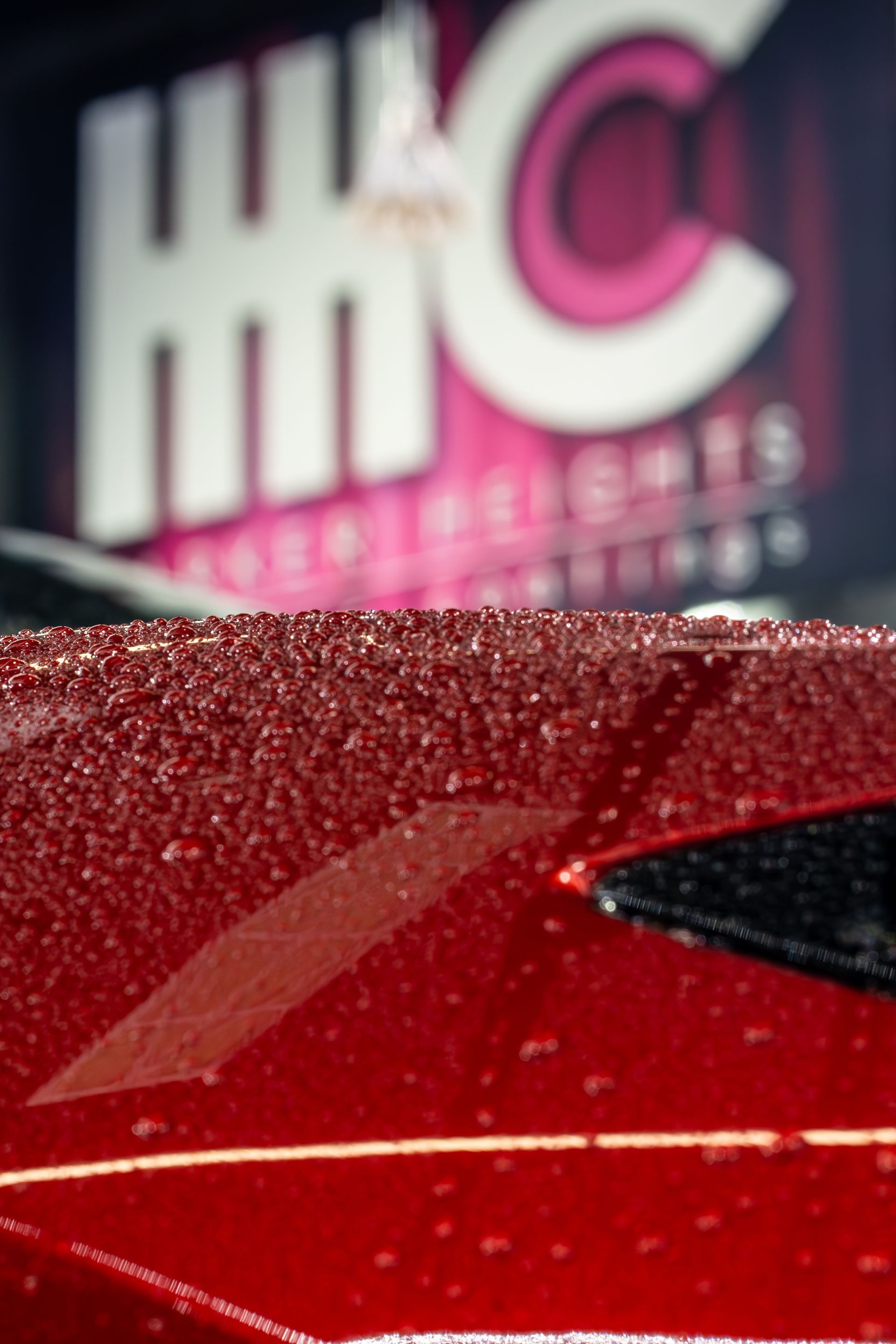 A close up of a red car with a hwc logo in the background