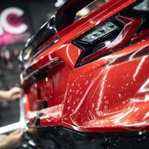 A close up of a red car being wrapped in plastic.