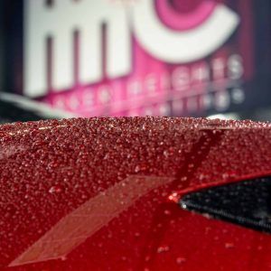 A close up of a red car with water drops on it
