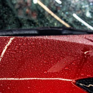 A close up of a red car with water drops on it