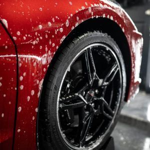 A close up of a red car being washed with soap.